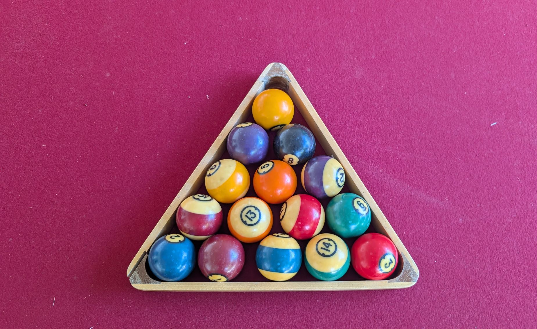 Pool balls racked on a red velvet billiards table