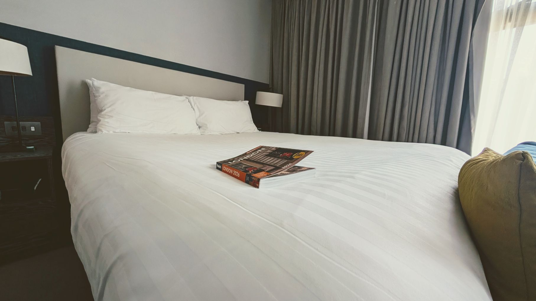 London travel guide on king bed with white linens in an IHG Staybridge London Vauxhall studio suite